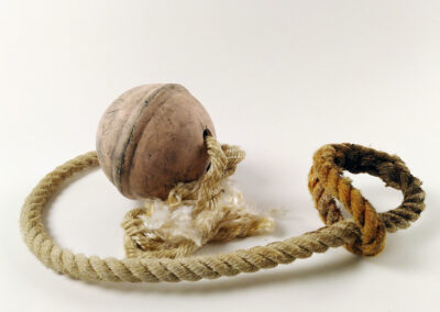 Un bout marin usé accroché à une bouée orange pâle en céramique. Ensemble photographié sur un fond blanc.