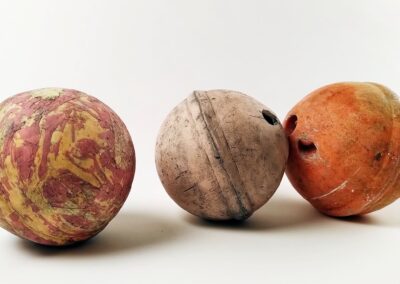 3 bouées marines alignées sur un fond blanc. Les bouées sont toutes dans les tons oranges. Elles semblent abîmées par le temps. Les deux bouées de gauche sont des reproductions réalistes en céramique de la bouée originale qui est le plus à droite de l'image.