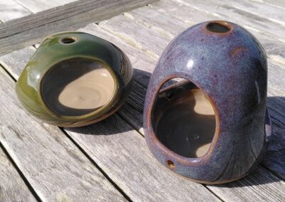Deux mangeoires à oiseaux en céramique sur une table en bois.